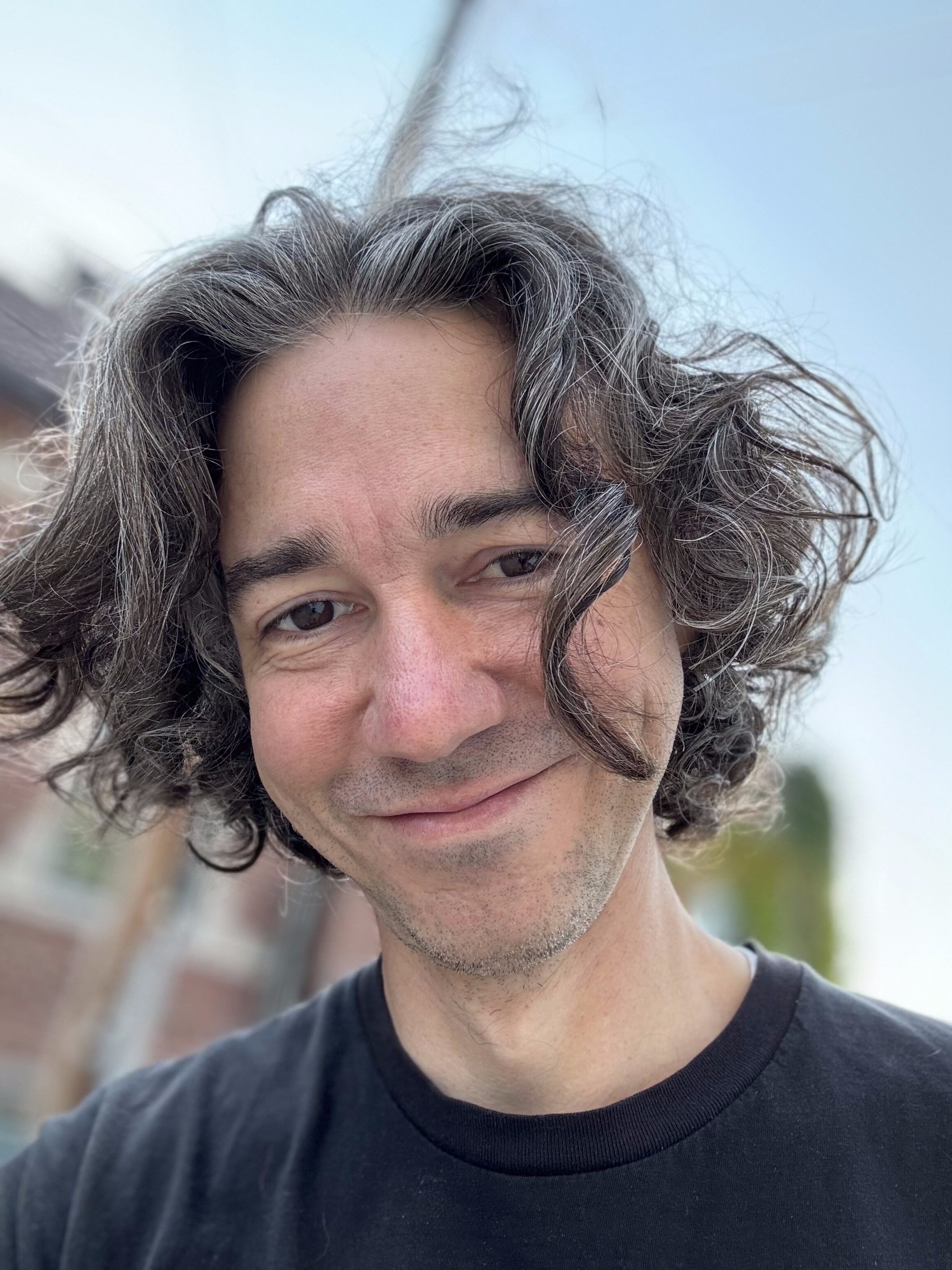 Headshot of man with wild long hair in a black t-shirt
