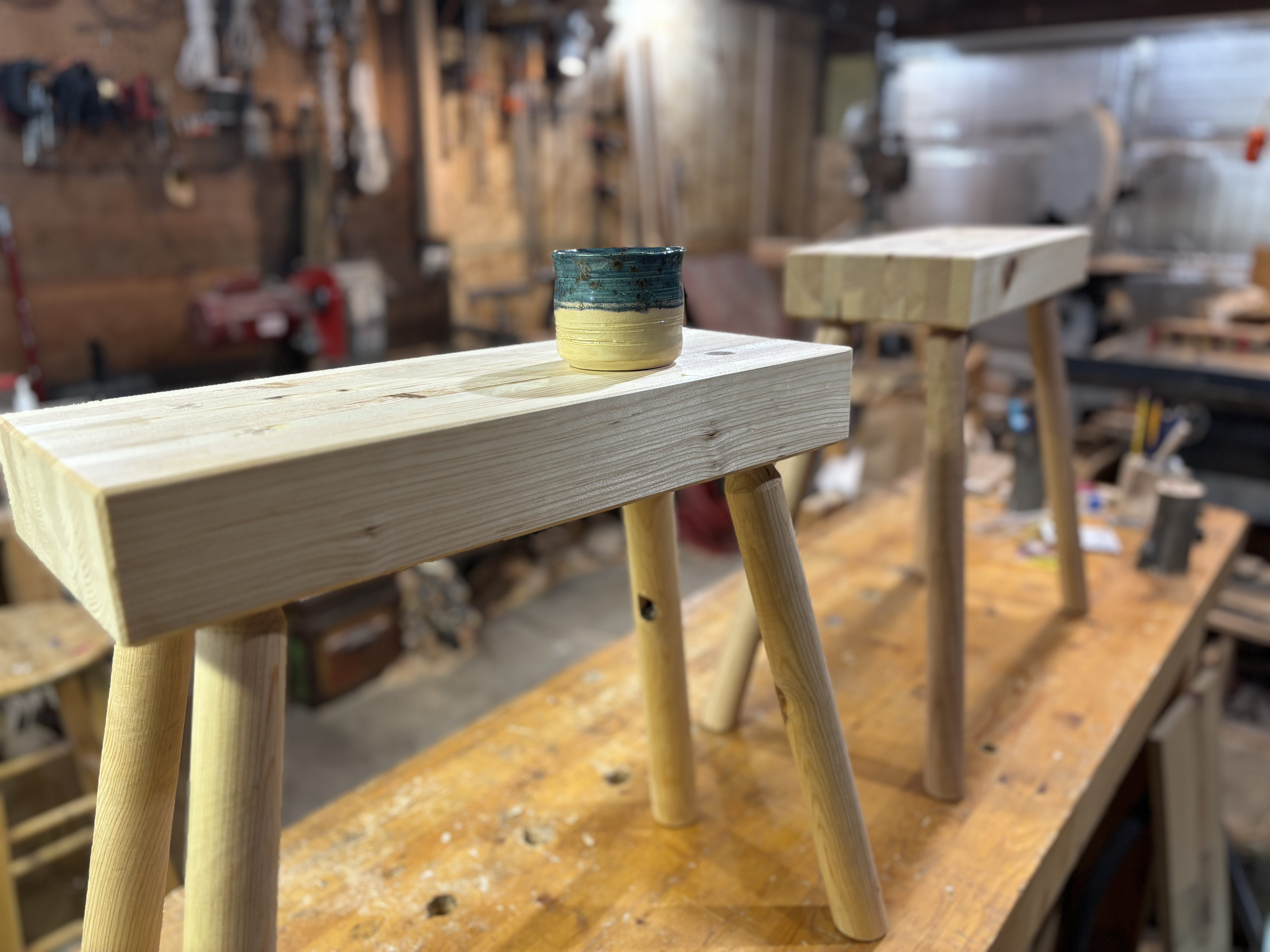 Two staked sawhorses in a workshop with a tea cup on top